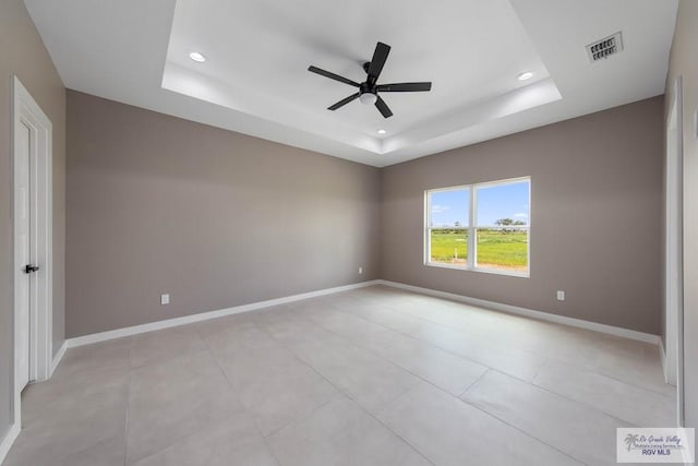 unfurnished room with ceiling fan and a raised ceiling