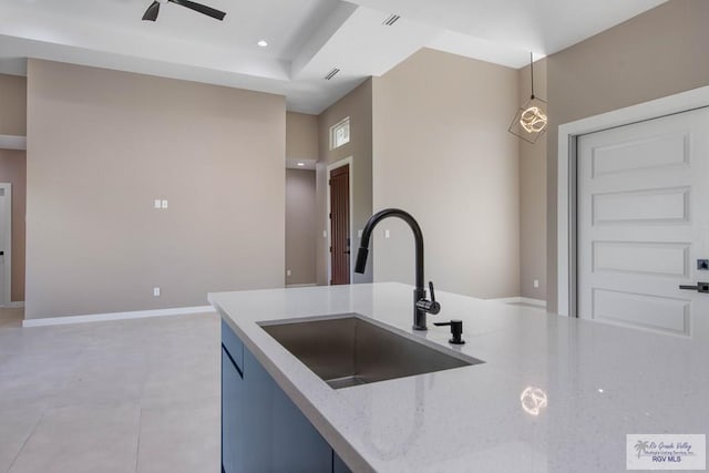 kitchen featuring blue cabinetry, light stone countertops, sink, ceiling fan, and hanging light fixtures