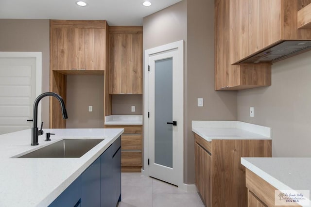 kitchen with light tile patterned floors, light stone counters, and sink