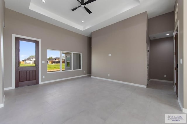 unfurnished living room featuring ceiling fan and a raised ceiling