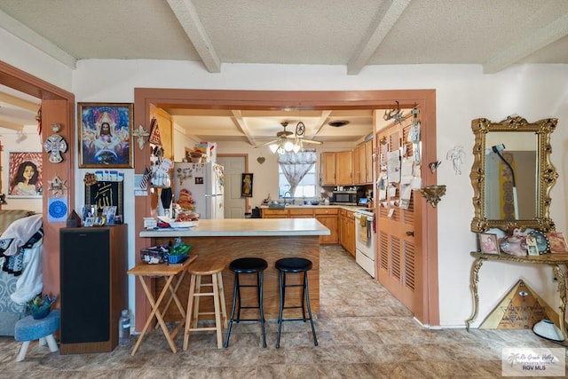 kitchen with a breakfast bar area, kitchen peninsula, beamed ceiling, and white appliances