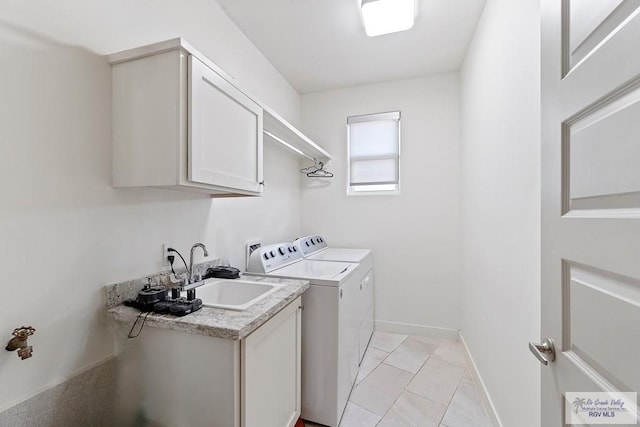 laundry area featuring cabinets, light tile patterned floors, washer and clothes dryer, and sink