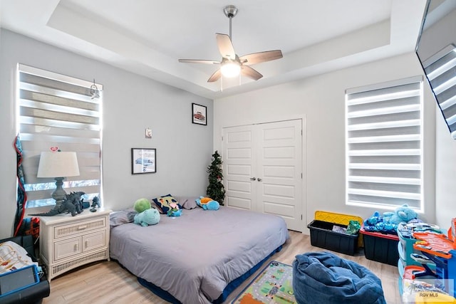 bedroom featuring a tray ceiling, ceiling fan, and light hardwood / wood-style flooring