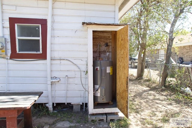 view of exterior entry featuring water heater and fence