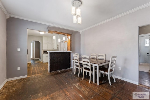 dining space with ornamental molding, arched walkways, dark wood-style flooring, and baseboards