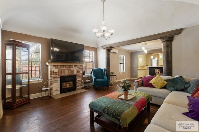 living room featuring ornate columns, a fireplace, baseboards, and wood finished floors