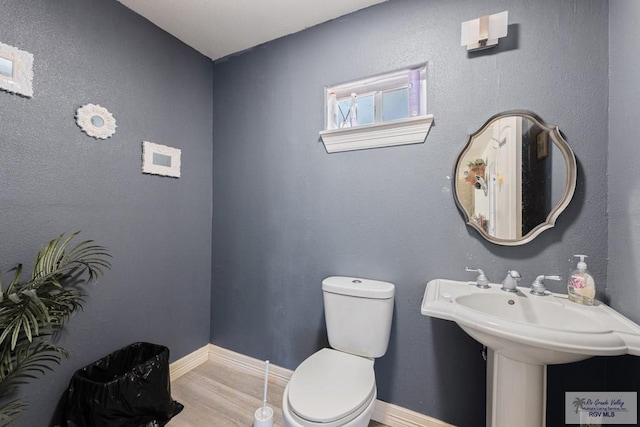 bathroom with wood finished floors, toilet, and baseboards