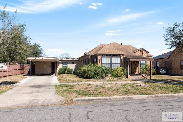 view of front of property with a carport, concrete driveway, and fence