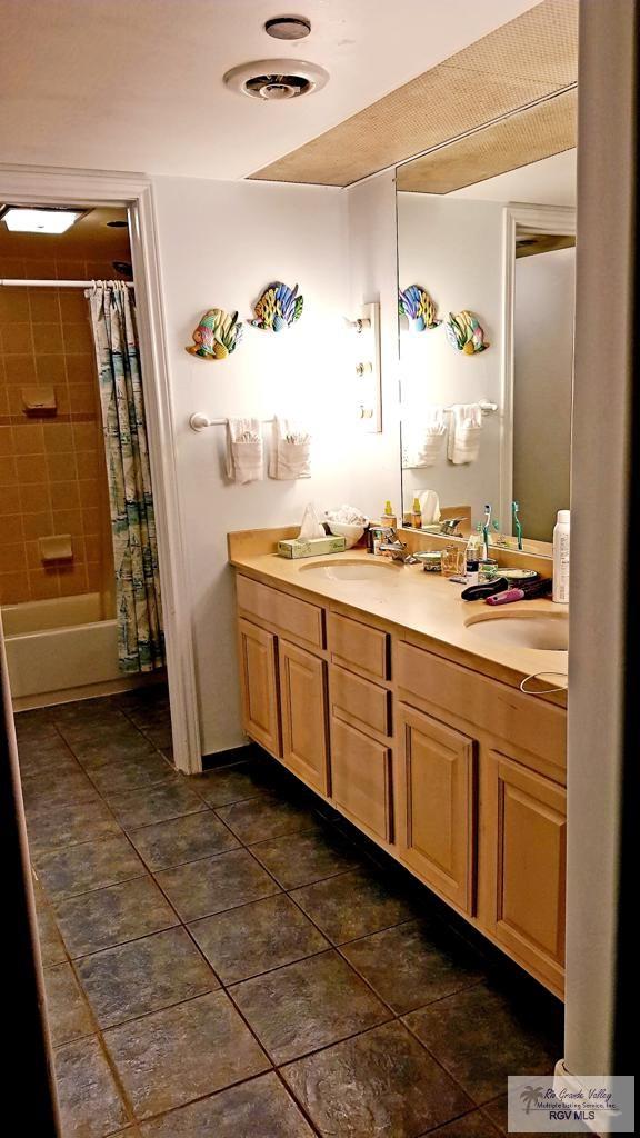 bathroom with shower / tub combo, vanity, and tile patterned floors