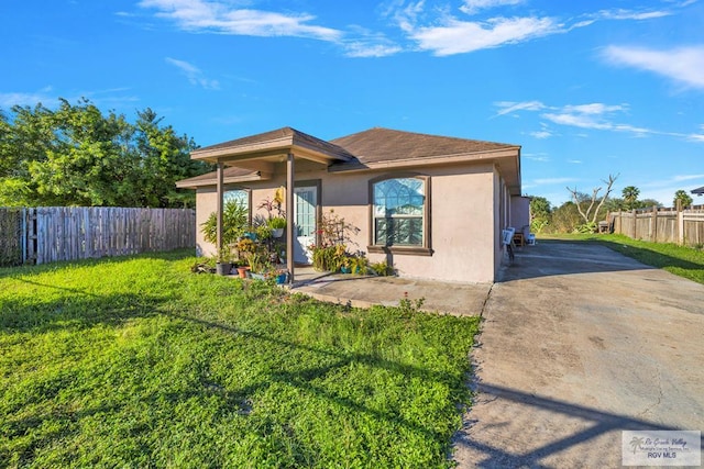 view of front of home featuring a patio area, fence, a front lawn, and stucco siding