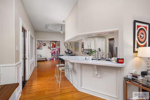 134 Camaguey Ave, Brownsville, TX 78526 - kitchen featuring light wood-style flooring, a breakfast bar, a peninsula, light countertops, and stainless steel refrigerator