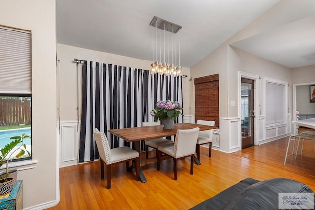 134 Camaguey Ave, Brownsville, TX 78526 - dining area featuring light wood-style flooring, lofted ceiling, a chandelier, and a wainscoted wall