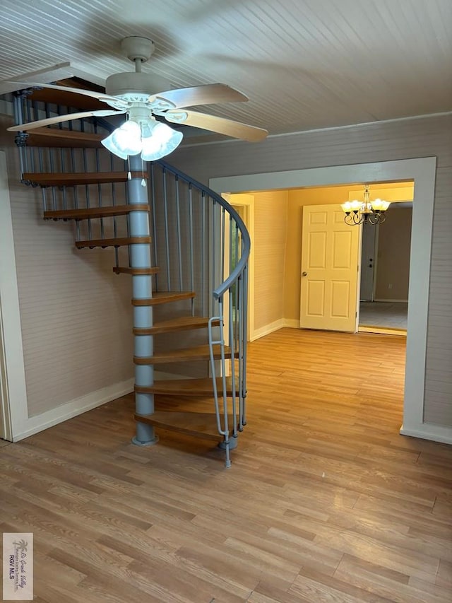 stairs with hardwood / wood-style floors and ceiling fan with notable chandelier