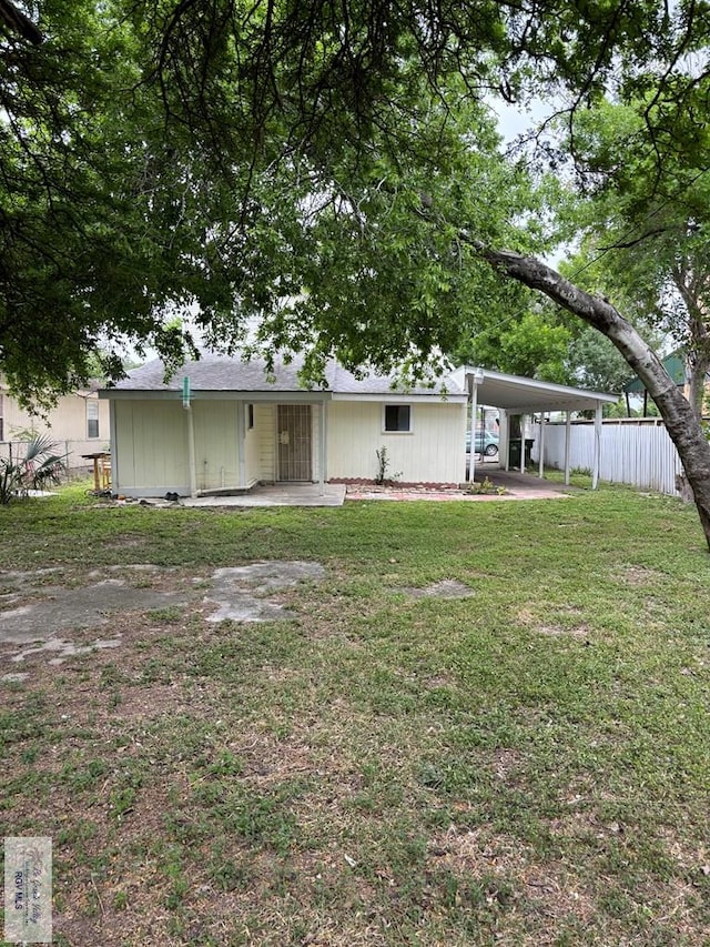 rear view of house featuring a yard and a carport