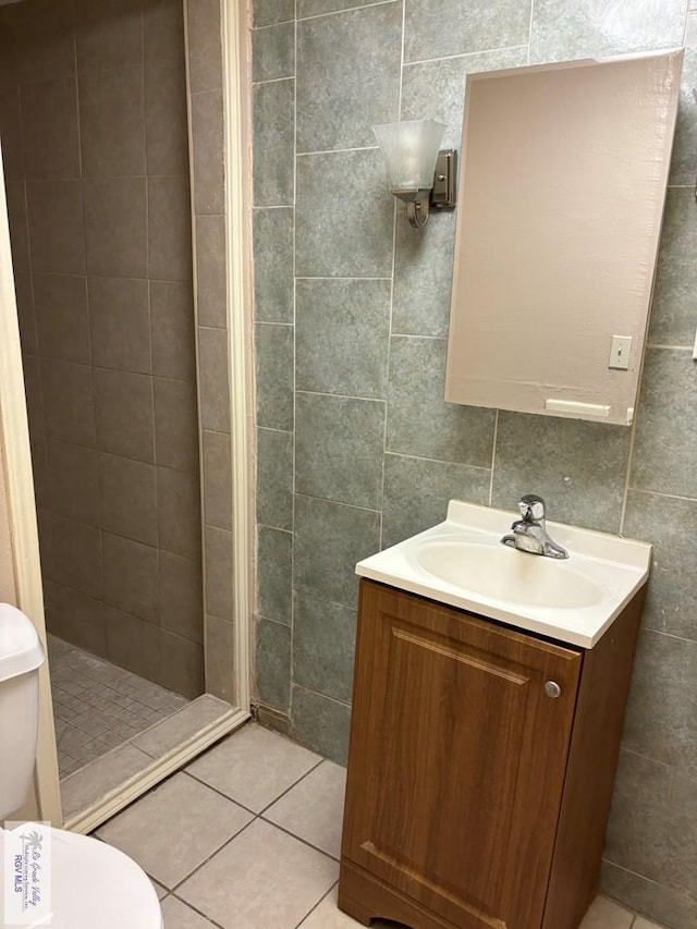 bathroom with vanity, a shower, tile patterned floors, toilet, and tile walls