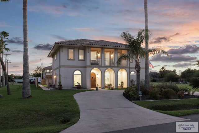 mediterranean / spanish-style house featuring a balcony and a yard