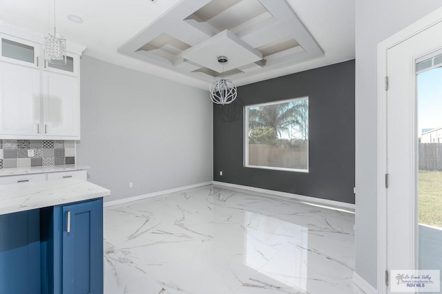 unfurnished dining area featuring a chandelier, plenty of natural light, and coffered ceiling