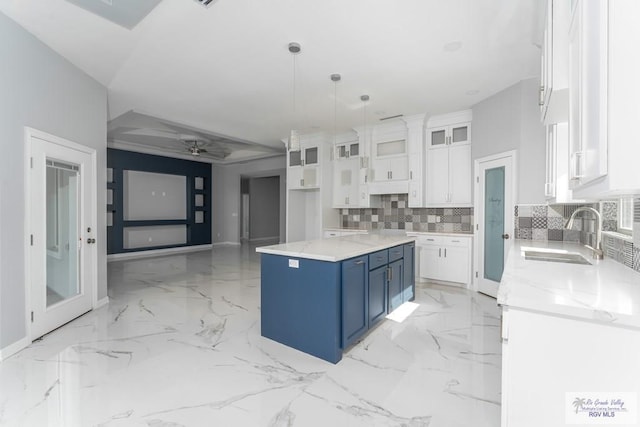 kitchen featuring blue cabinetry, sink, a kitchen island, decorative light fixtures, and white cabinets