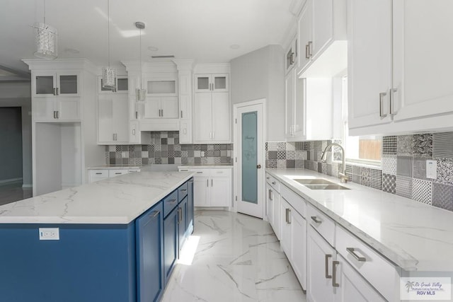 kitchen with light stone counters, sink, pendant lighting, white cabinets, and a kitchen island