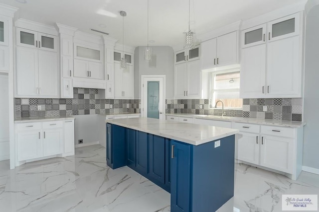 kitchen featuring white cabinets, a kitchen island, and light stone countertops