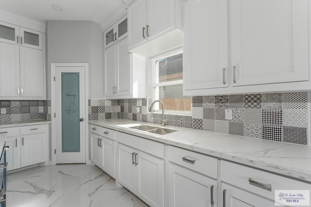 kitchen featuring white cabinets, decorative backsplash, light stone countertops, and sink