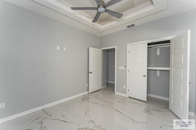 unfurnished bedroom with ceiling fan, a closet, and a tray ceiling