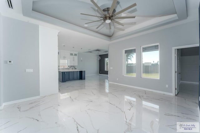 unfurnished living room featuring a raised ceiling and ceiling fan