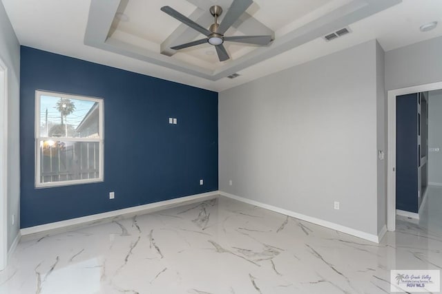 spare room featuring a raised ceiling and ceiling fan