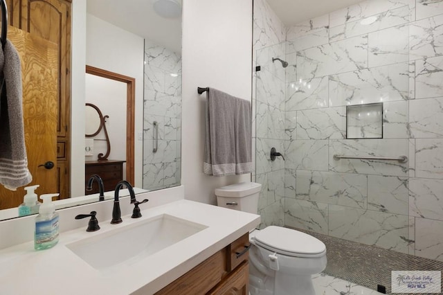 full bathroom featuring a tile shower, vanity, marble finish floor, and toilet