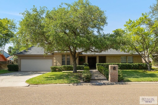 ranch-style home with brick siding, an attached garage, a front lawn, and concrete driveway