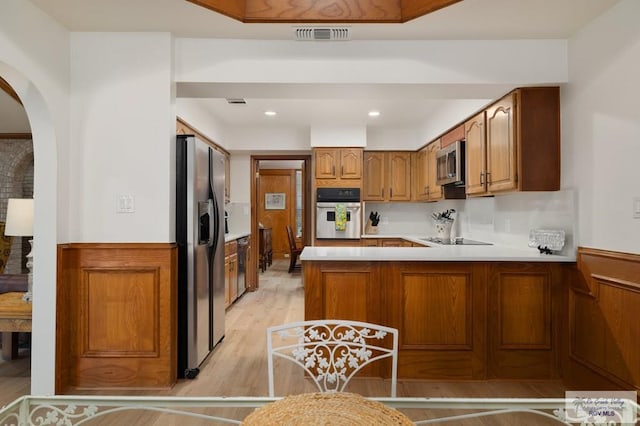 kitchen featuring a peninsula, visible vents, appliances with stainless steel finishes, light countertops, and brown cabinets