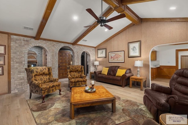 living area featuring arched walkways, a ceiling fan, visible vents, vaulted ceiling with beams, and light wood finished floors
