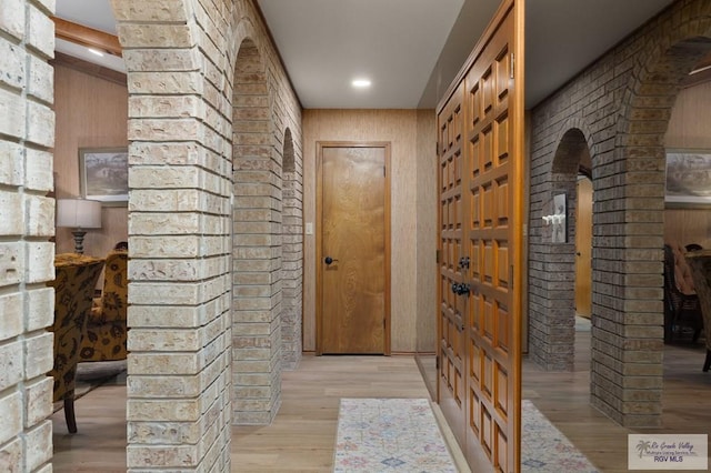 interior space featuring brick wall, arched walkways, light wood-type flooring, and recessed lighting