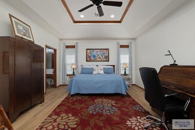 bedroom with light wood-style flooring, ceiling fan, ornamental molding, and a raised ceiling
