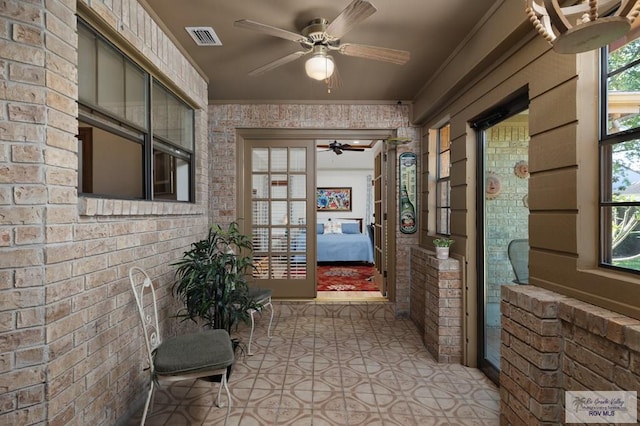 property entrance featuring ceiling fan, visible vents, and brick siding