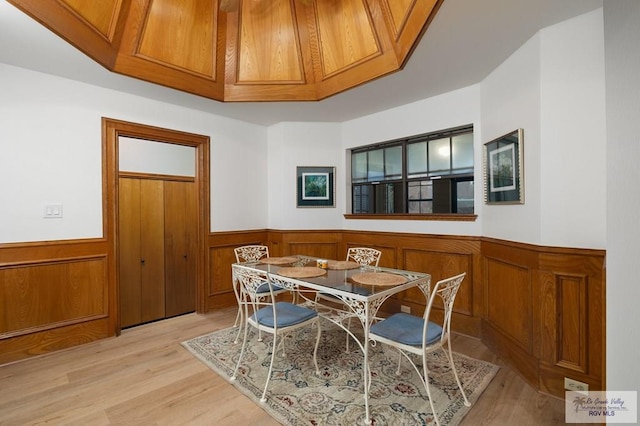 dining area with light wood-type flooring and a wainscoted wall