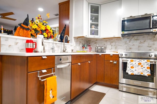 kitchen with appliances with stainless steel finishes, backsplash, ceiling fan, white cabinetry, and light tile patterned flooring