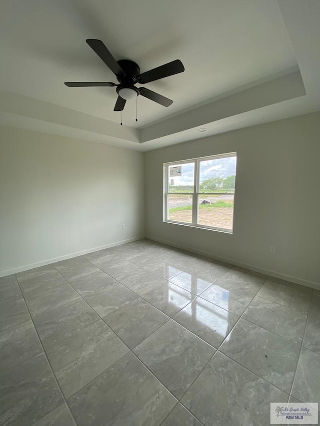 unfurnished room featuring ceiling fan and a raised ceiling