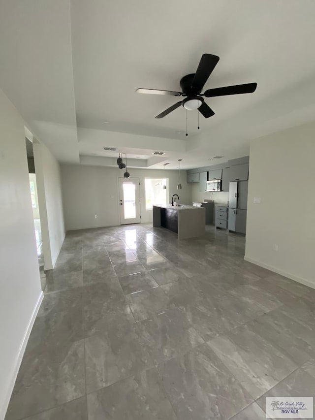 unfurnished living room with ceiling fan and sink