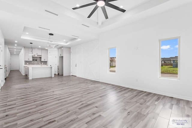 9718 Alexis Ave, Harlingen, TX 78550 - unfurnished living room featuring a raised ceiling, visible vents, light wood-style flooring, and ceiling fan