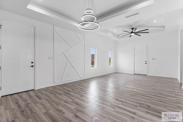 9718 Alexis Ave, Harlingen, TX 78550 - unfurnished living room featuring a tray ceiling, light wood-style floors, ceiling fan, and visible vents