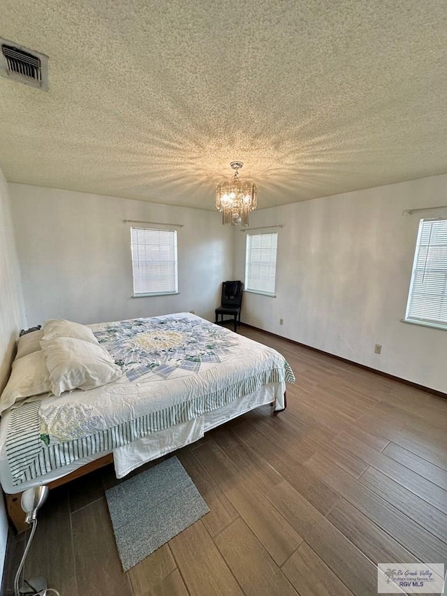 bedroom with multiple windows, a textured ceiling, and hardwood / wood-style flooring