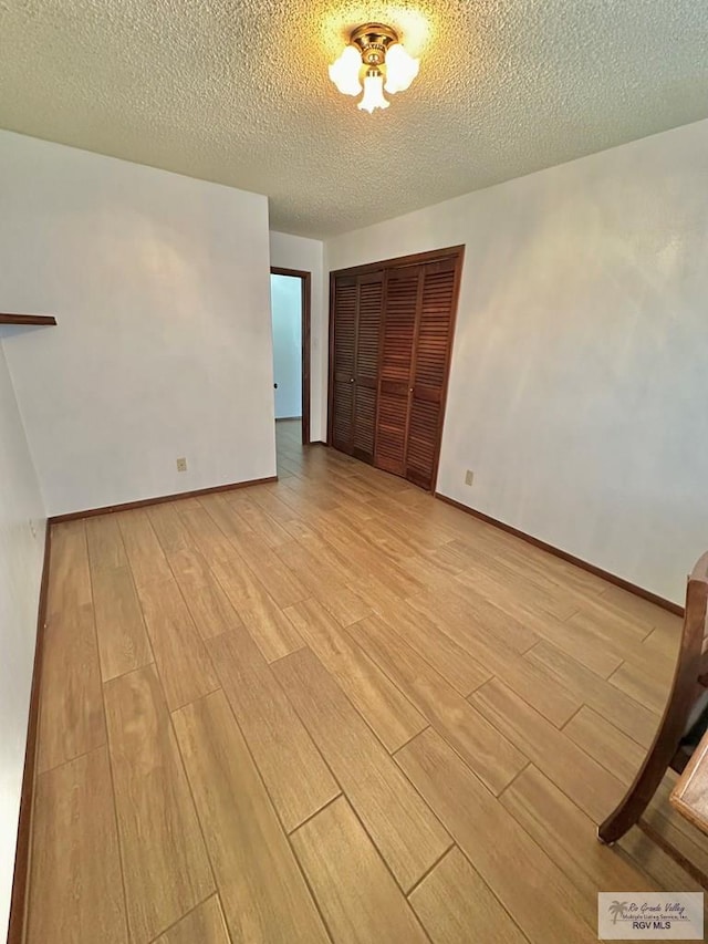 unfurnished bedroom featuring a closet, a textured ceiling, and light hardwood / wood-style flooring