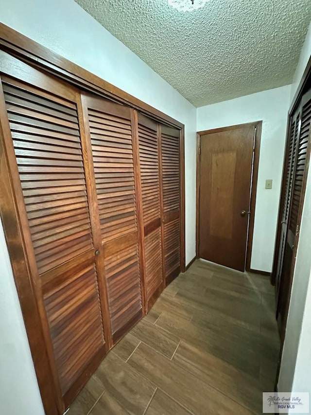 hall with dark hardwood / wood-style flooring and a textured ceiling