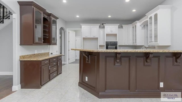 5443 Autumn Mist Ln, Brownsville, TX 78526 - kitchen featuring black oven, recessed lighting, baseboards, dark brown cabinets, and a breakfast bar