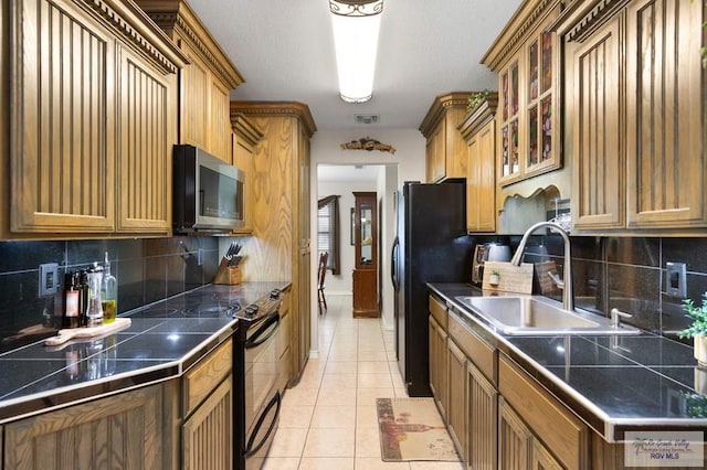 kitchen featuring sink, light tile patterned floors, black appliances, and tasteful backsplash