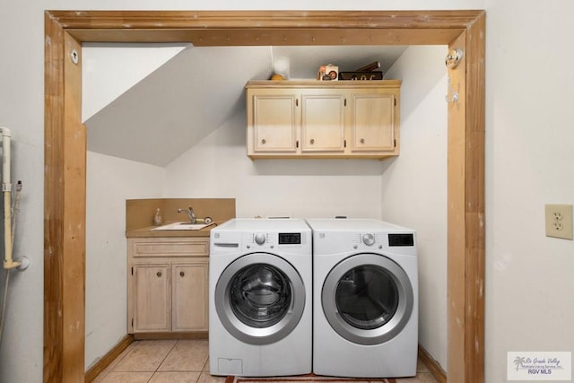 laundry room with light tile patterned floors, sink, washing machine and clothes dryer, and cabinets