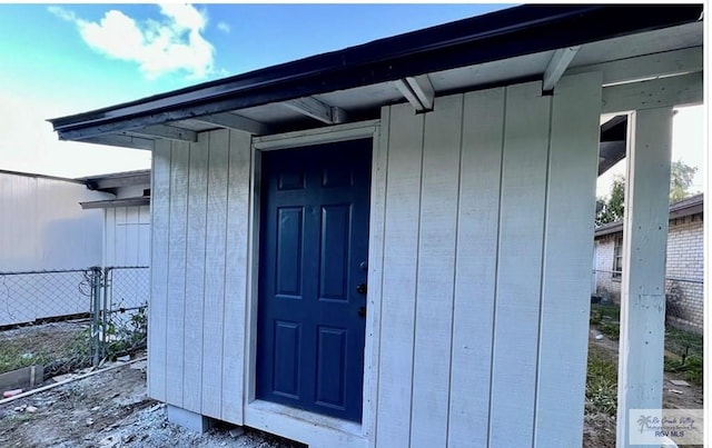 entrance to property with board and batten siding and fence