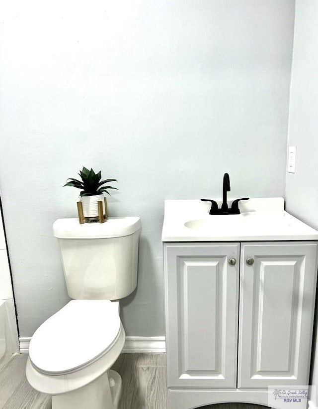 bathroom featuring vanity, toilet, and baseboards