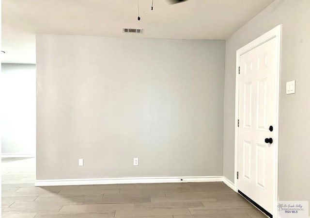 empty room with visible vents, baseboards, and wood finished floors